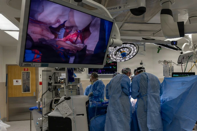 Surgeons operate while viewing the procedure on a large screen.